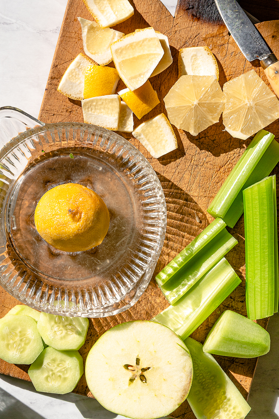 Ingredients of lemon, cucumber, apple, and celery are cut into chunks for juice.