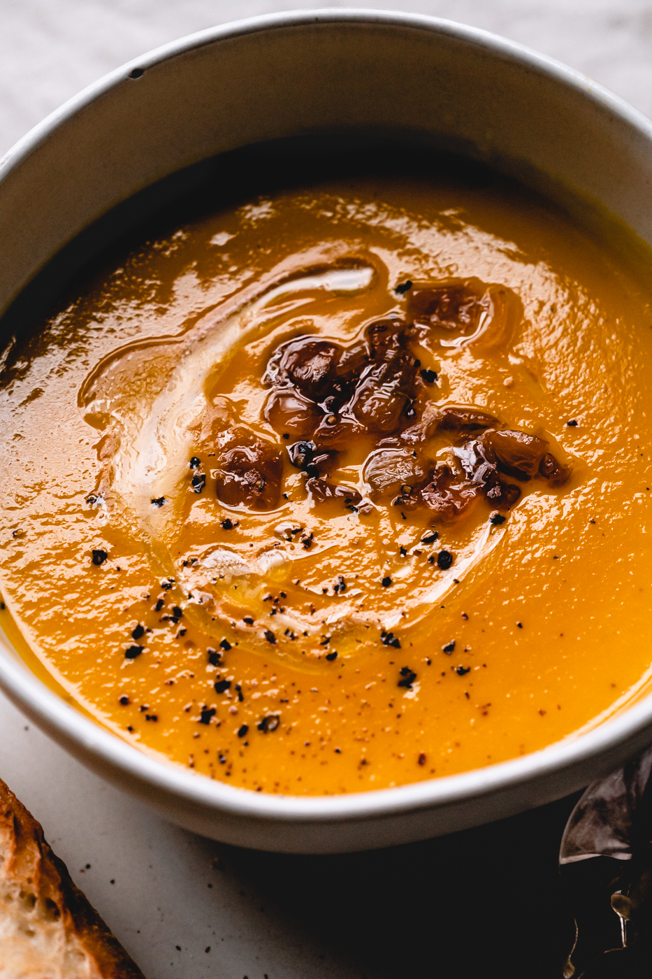 A zoomed in photo of the butternut squash soup showing the luscious consistency. The soup is topped with a drizzle of olive oil, extra caramelized onions, and fresh cracked pepper. 