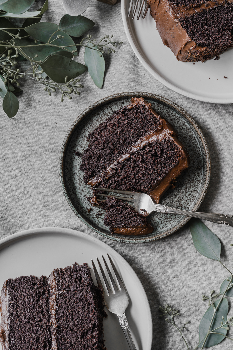 Three slices of gluten-free chocolate cake on their own plate with forks next to them.