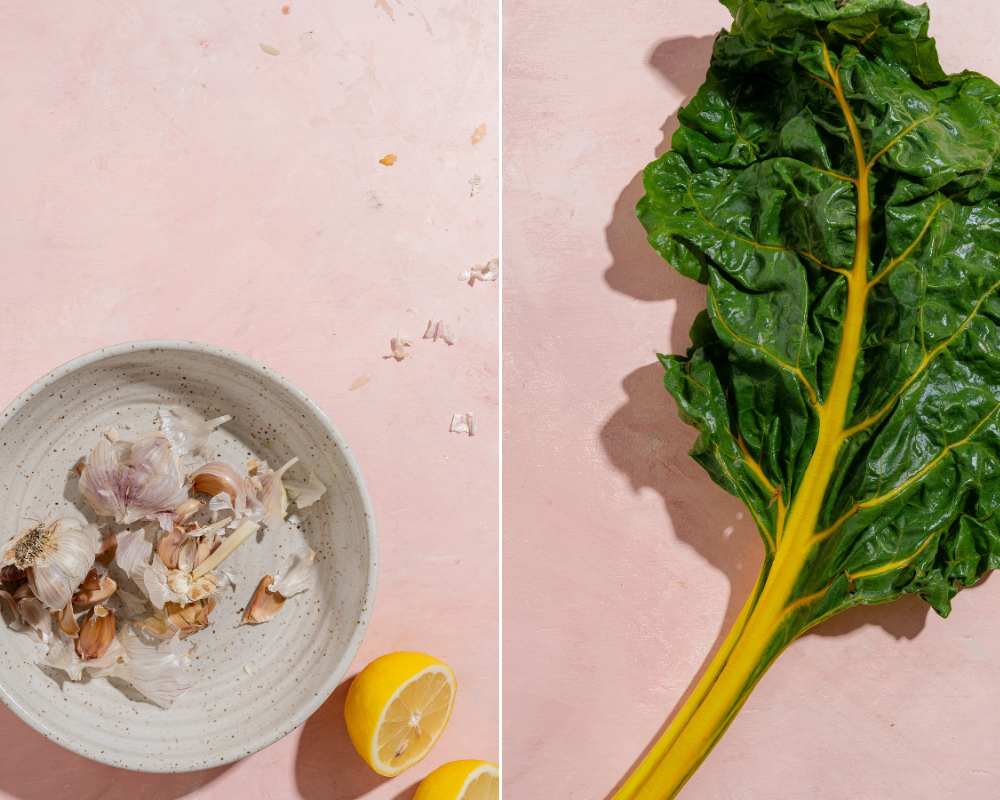 A collage of two images side by side. The first is of a ivory speckled bowl with garlic bulbs and and cloves broken up with a lemon cut in half in the bottom right hand corner. The other images of a simple shot of a chard leaf that has a yellow stem. 