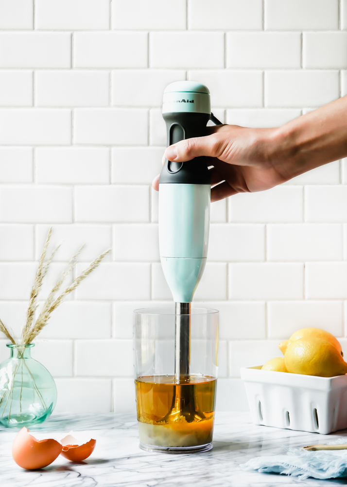 Hand holding an immersion blender about to make a roasted garlic aioli sauce.