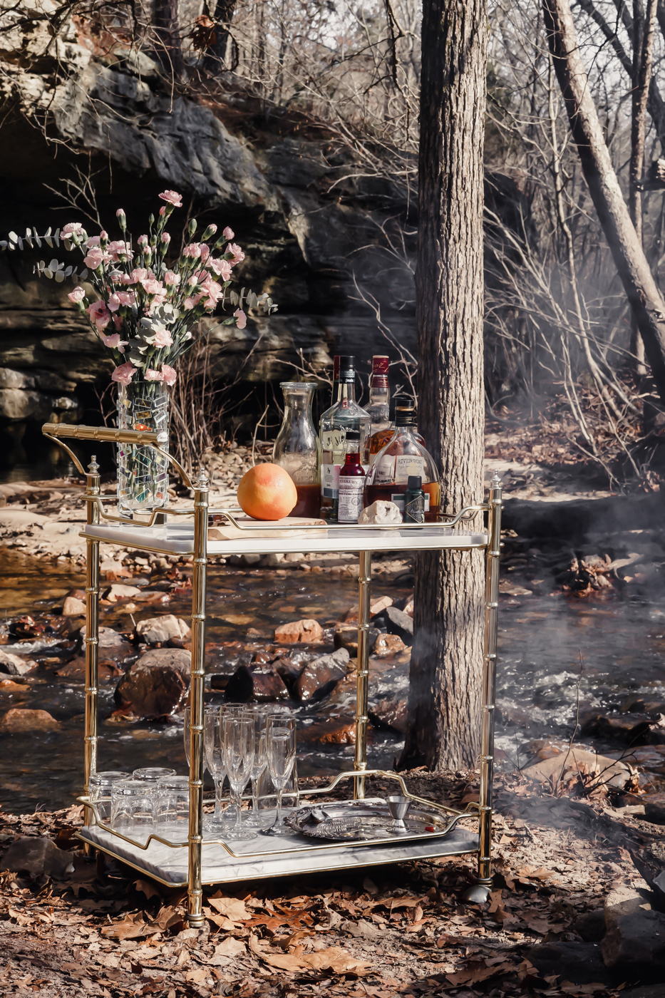An antique bar cart on a river bank with a cliff in the background.