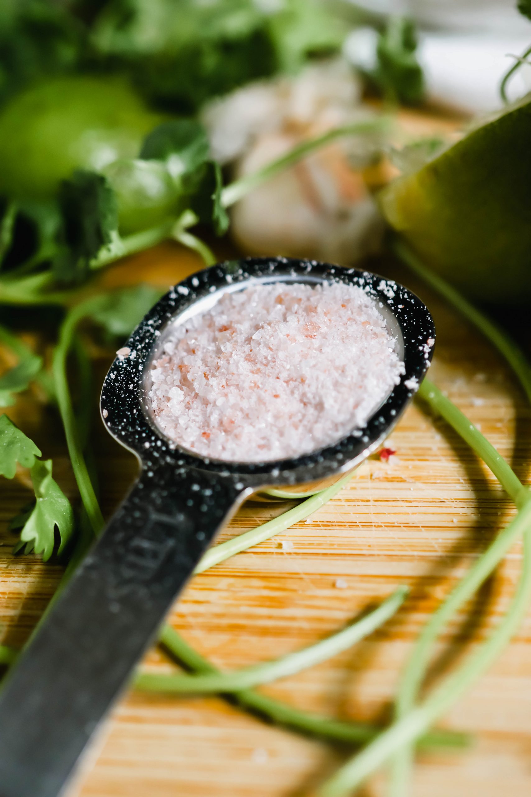 Himalayan pink salt is being measured in a tablespoon.