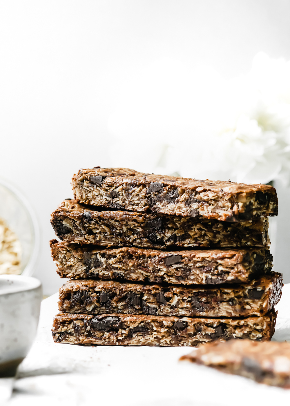 A close up of a stack of Collagen Tahini Granola Bars that shows chocolate chunks.