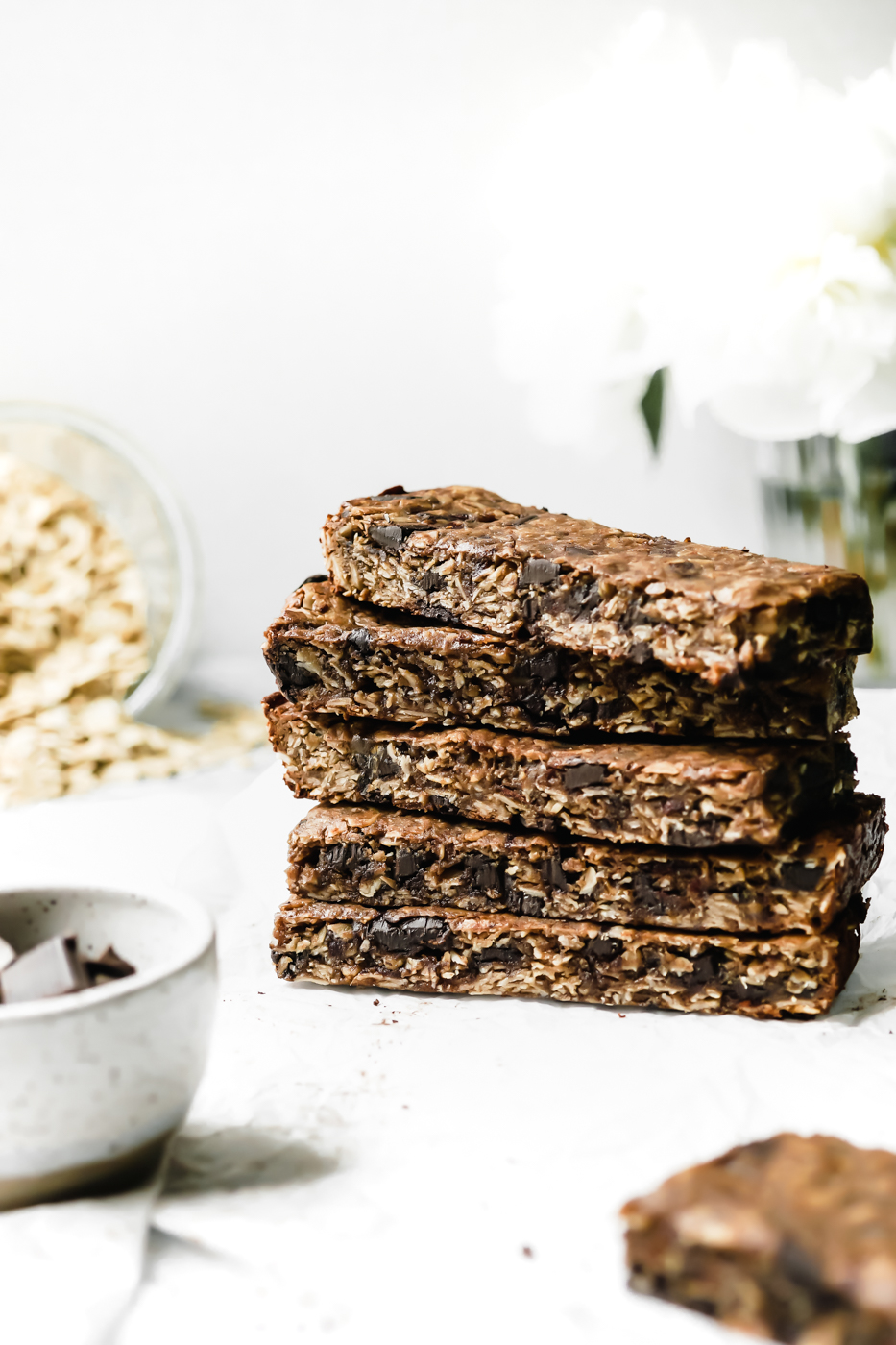 A stack of Collagen Tahini Granola Bars with gluten-free oats in the background.