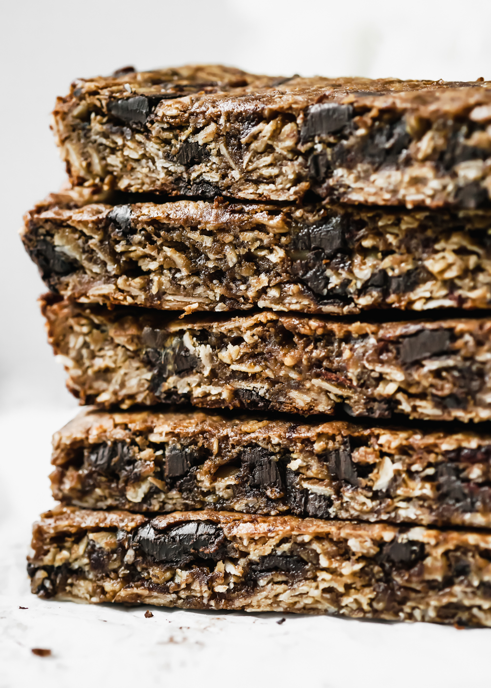 A macro shoot of a stack of Collagen Tahini Granola Bars that shows a chewy texture and chocolate chunks.