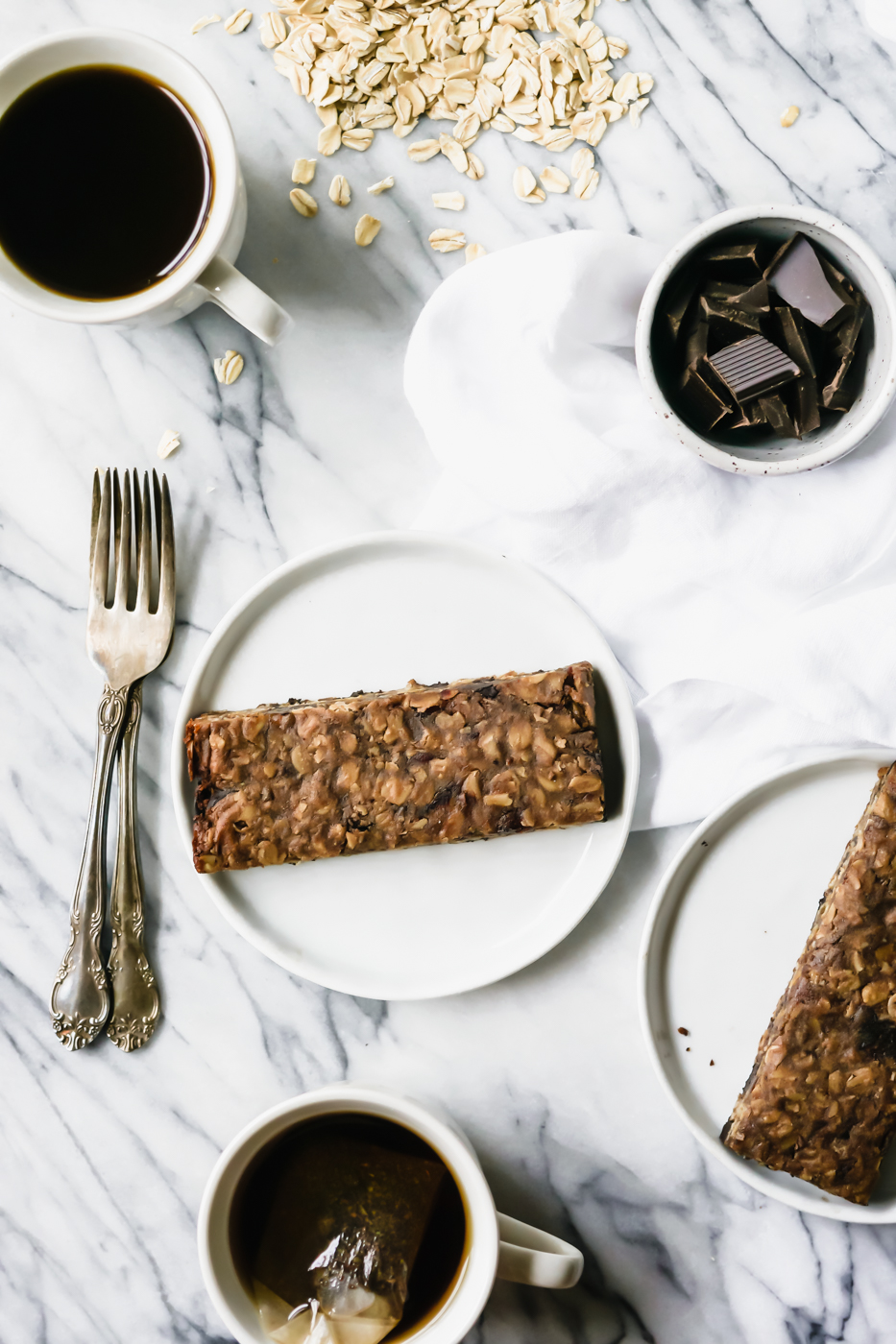 Two Collagen Tahini Granola Bars on a plate with a cup of tea and a cup of coffee.