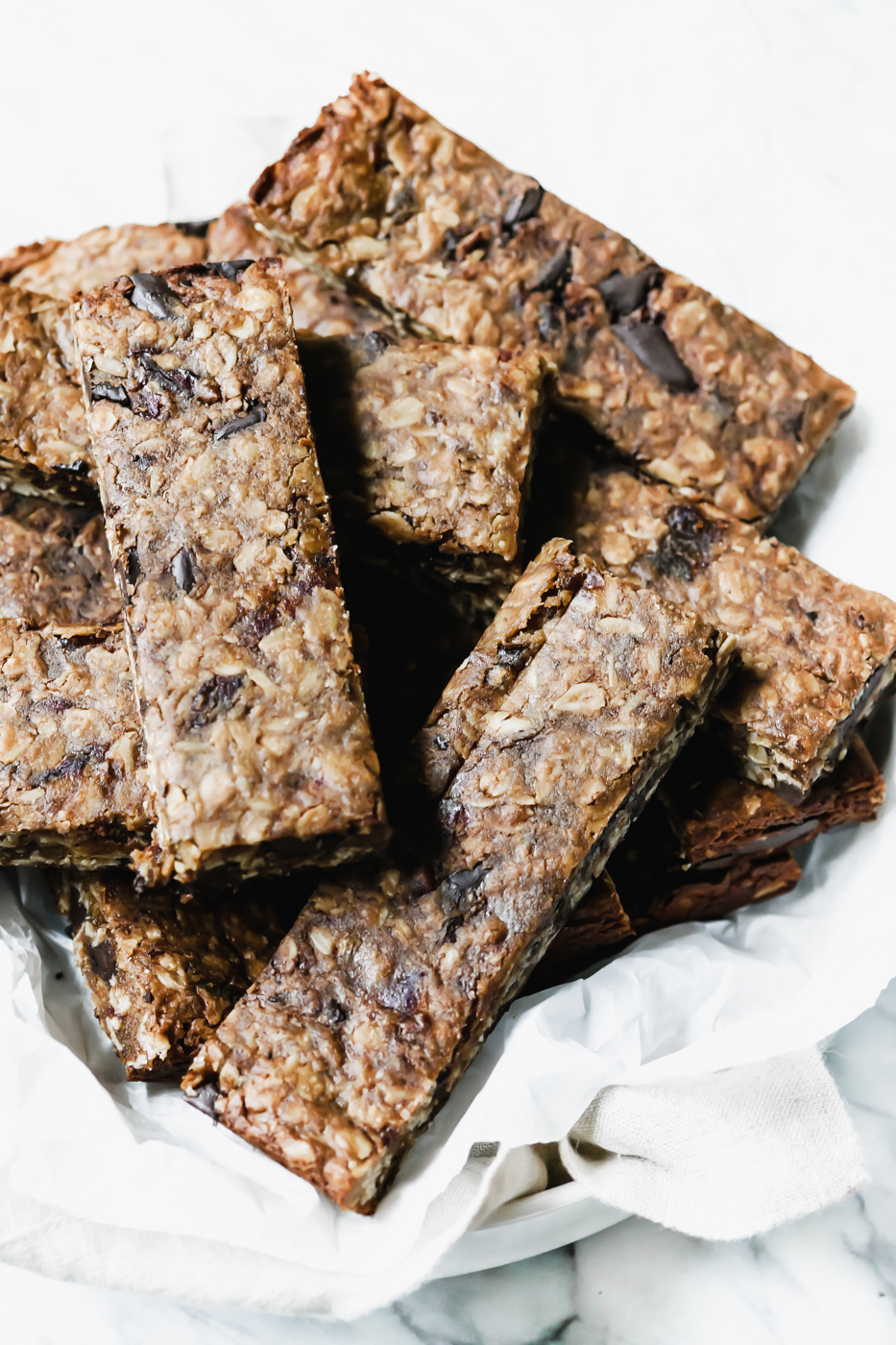 A pile of Collagen Tahini Granola Bars in a bowl with a white linen.